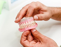 Close-up of hands working with dentures in Ann Arbor, MI