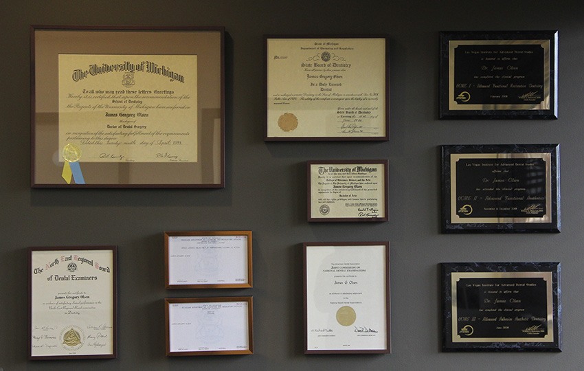 Wall of James Olsen's dental certificates and awards