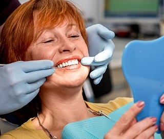 Senior woman and dentist looking at smile in mirror after restorative dentistry