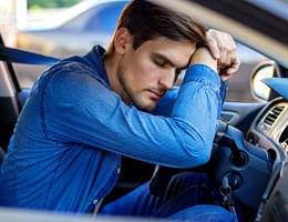 Man falling asleep in car in need of sleep apnea therapy