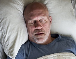 Man sleeping soundly in bed after receiving sleep apnea treatment
