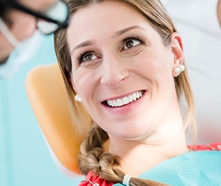 Woman in dental chair discussing dental bridge tooth replacement