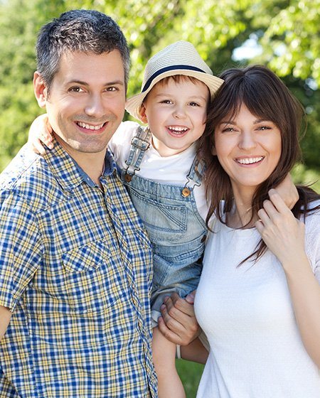 Mother father and young child smiling outdoors