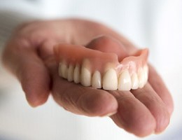 Hand holding upper denture