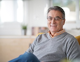 Senior man in grey shirt resting on couch