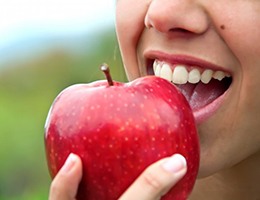 close up person about to bite apple after dental bonding treatment