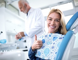 woman giving thumbs up in dental chair after dental bonding treatment