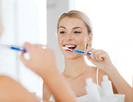 Woman brushing teeth to prevent dental emergencies in Ann Arbor