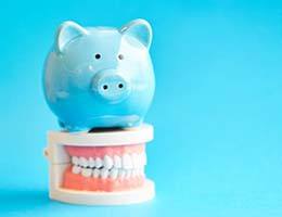 Blue piggy bank atop model teeth represent cost of Invisalign