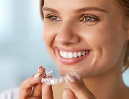 Smiling woman with beautiful smile holding Invisalign