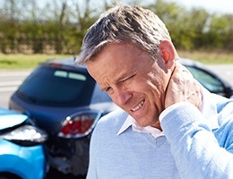 Man holding neck in pain after car accident caused by sleepiness