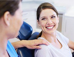 Smiling woman in dental chair for T M J therapy treatment
