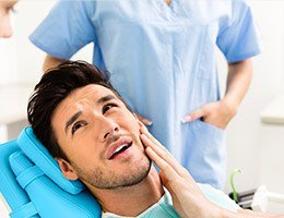 Man in dental chair holding jaw before T M J therapy
