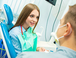 A young woman listens as her dentist discusses the process of receiving veneers