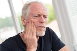 Older man in Ann Arbor touching jaw in pain 
